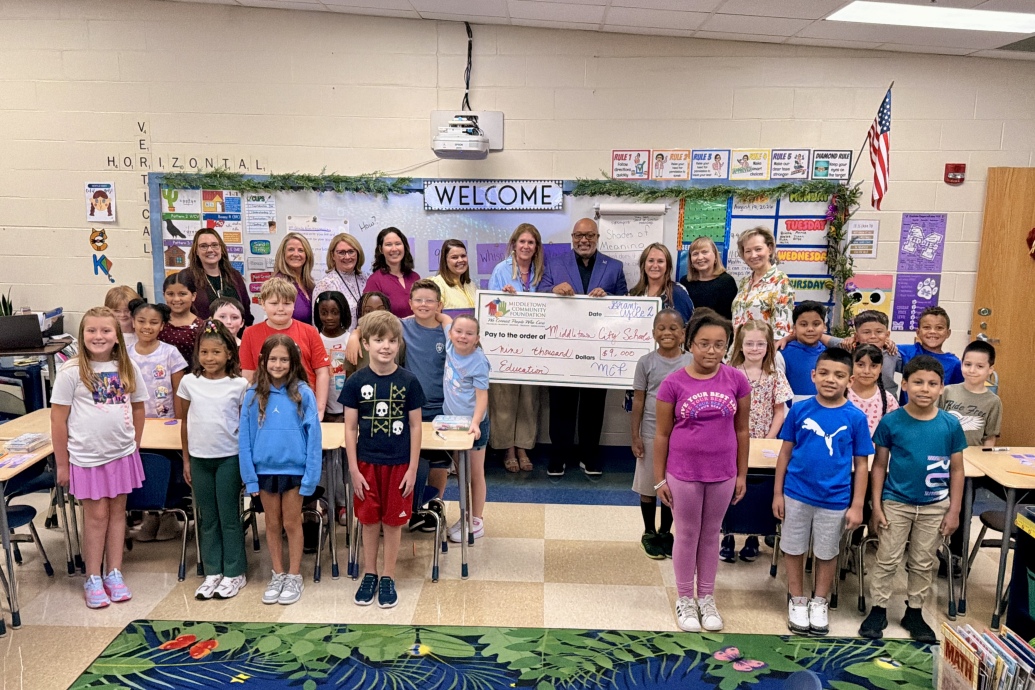 Classroom of students and district leaders with a large check for the grant funds